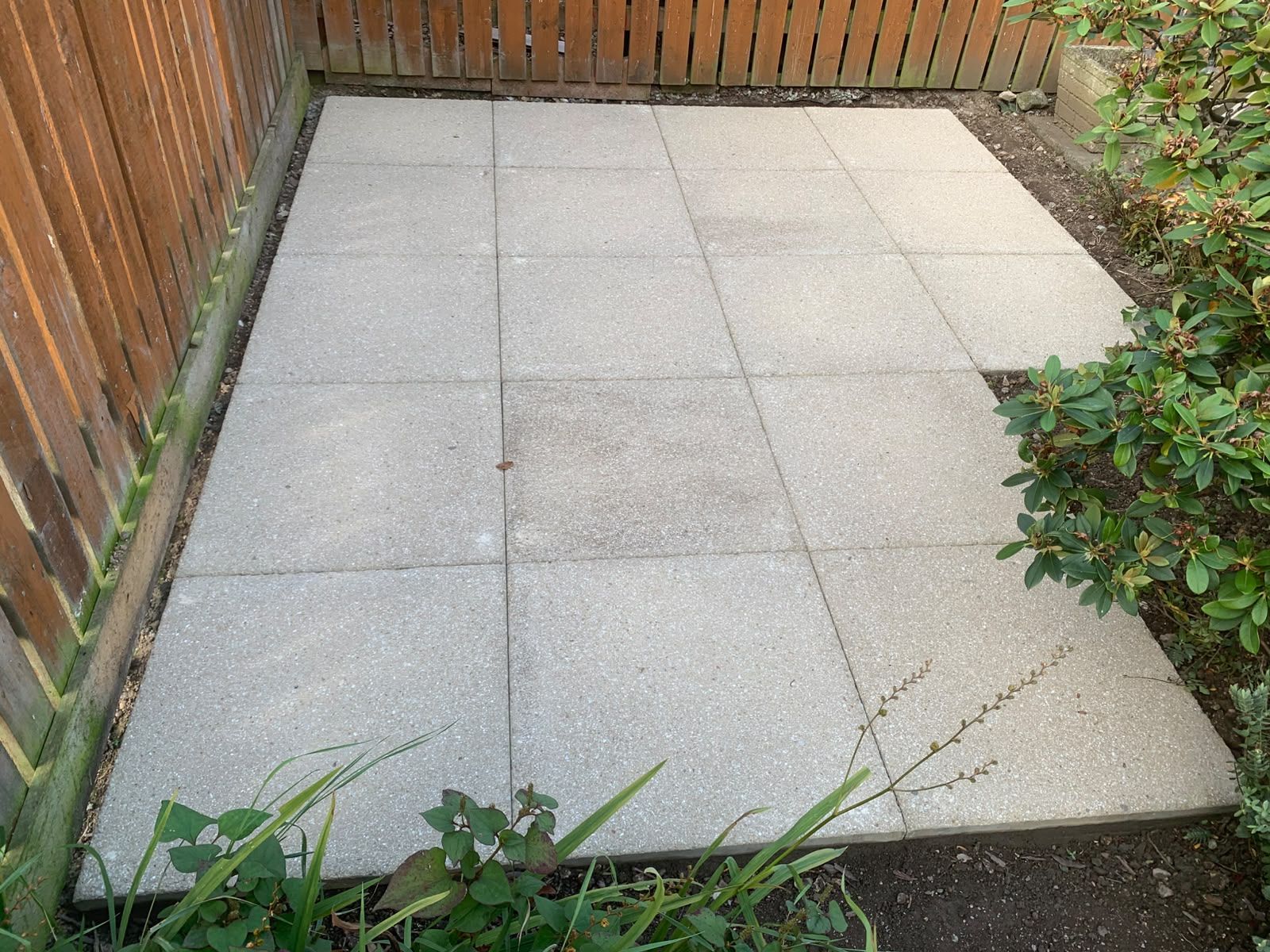 Grey paving slabs laid as a small patio beside a timber fence