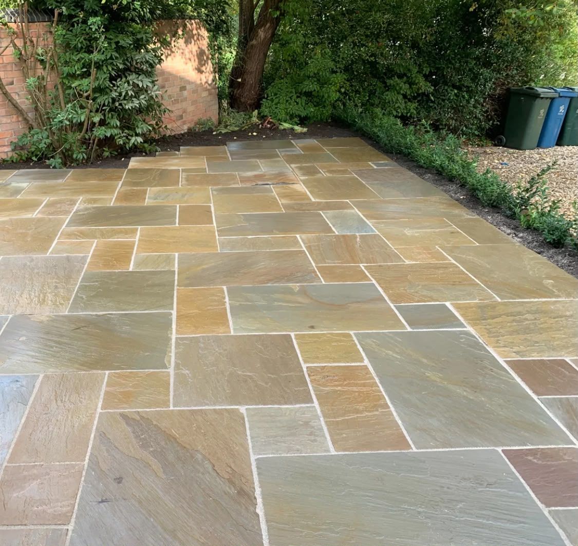Indian sandstone patio in mixed buff and grey tones next to a garden border